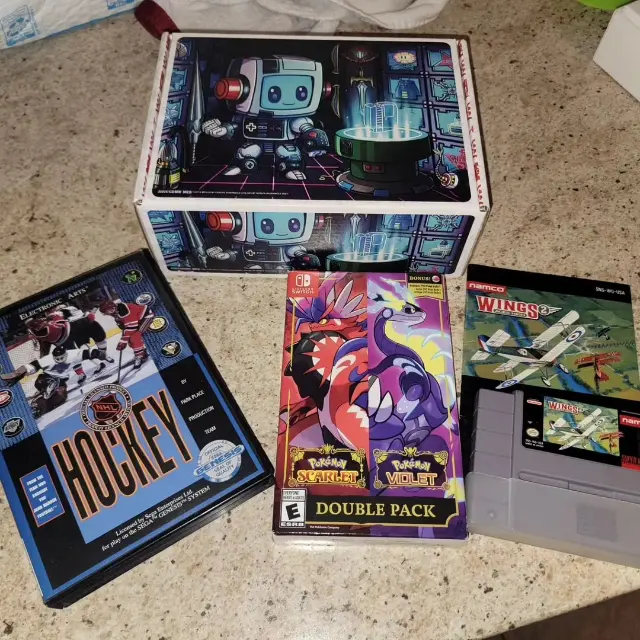 Awesome Nes GGRetroBox with the games Pokemon Scarlet and Violet Double Pack (Nintendo Switch), Wings (NES), and NHL Hockey (Sega Gensis)
