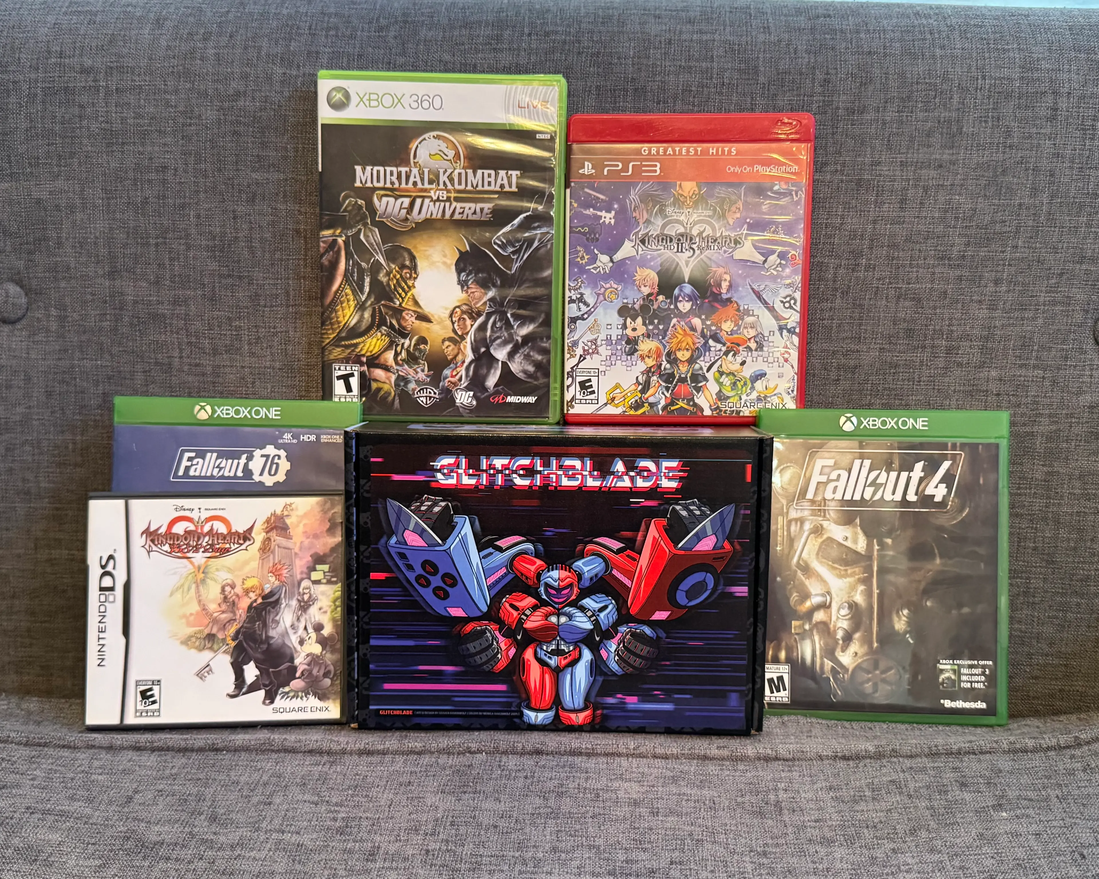 Glitchblade GGRetroBox with the games Mortal Kombat vs DC Universe (Xbox 360), Kingdom Hearts II.5 (PS3), Fallout 76 (Xbox One), Kingdom Hearts 365/2 Days (DS), and Fallout 4 (Xbox One)