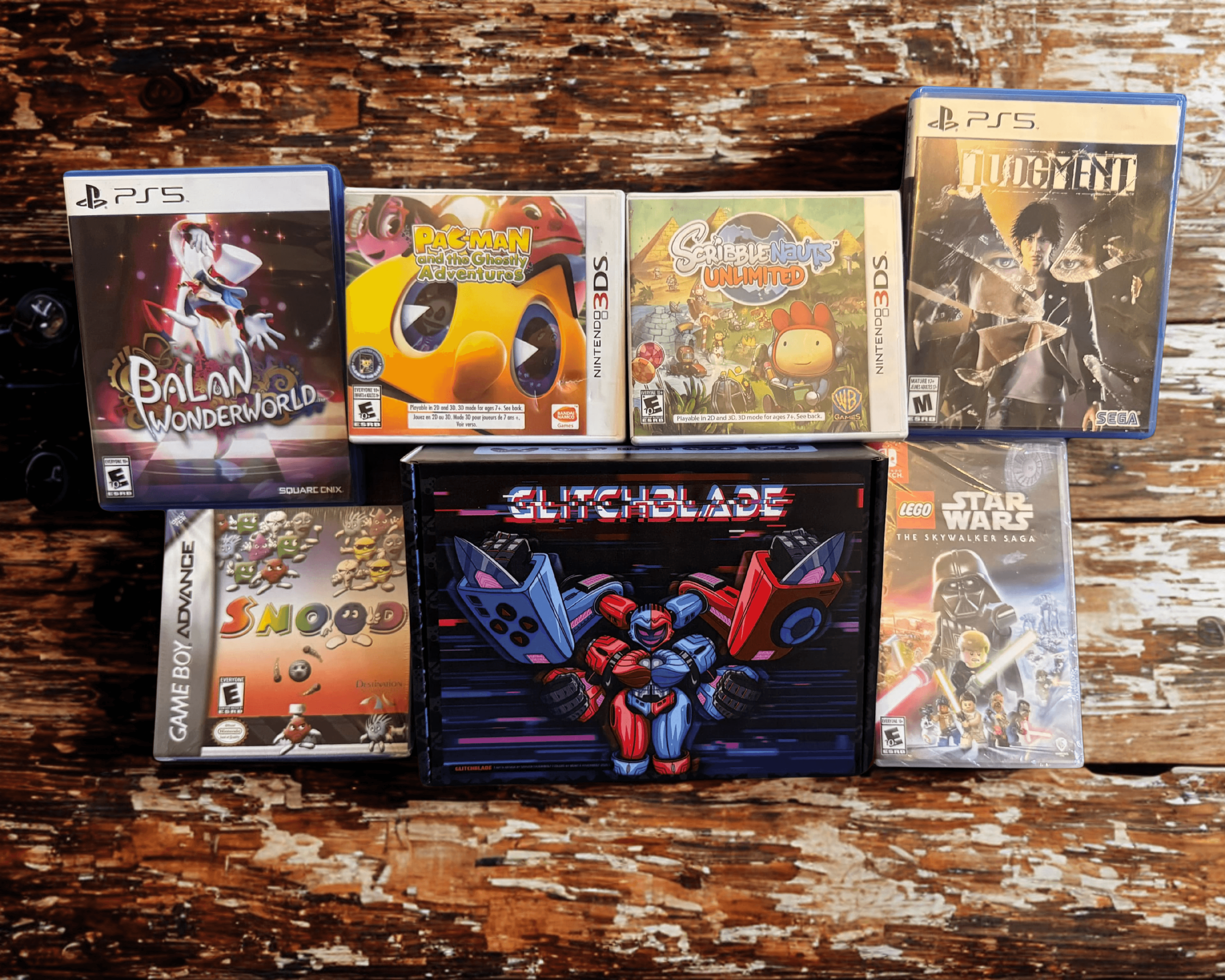 Glitchblade GGRetroBox with the games Balan Wonderworld (PS5), Pac-Man and the Ghostly Adventures (3DS), Scribblenauts Unlimited (3DS), Judgment (PS5), Snood (Game Boy Advance), and LEGO Star Wars The Skywalker Saga (Switch)